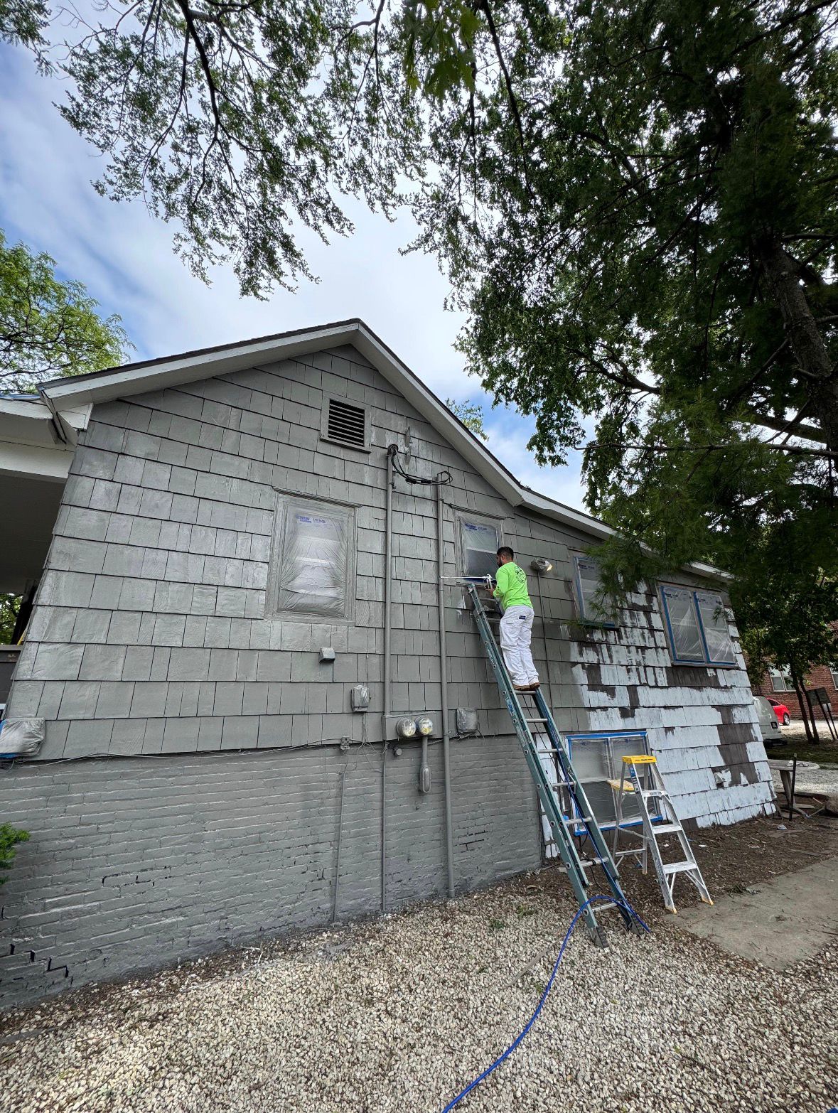 Painter on ladder working on siding, blue sky
